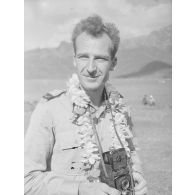[Portrait d'un marin. Il porte un collier de fleurs et un appareil photo autour de son coup, s.d].<br>