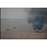 Des chars AMX-30 B2 du 4e RD (régiment de dragons) progressent en bordure de l'axe Texas et dépassent un camion-citerne irakien en feu. Les chars portent des panneaux d'identification air-sol allié.