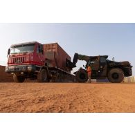 Des soldats du 121e régiment du train (RT) chargent un container à bord d'un semi-remorque au moyen d'un chariot Manitou sur la plateforme logistique de PK 11, au Niger.