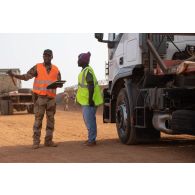 Le sergent Abou de l'escadron de ravitaillement du 121e régiment du train (RT) discute avec le chauffeur d'un semi-remorque nigérien sur la plateforme logistique de PK 11, au Niger.