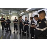 Des soldats de l'équipe d'intervention participent à un briefing au terme d'un exercice incendie à bord du porte-hélicoptères amphibie (PHA) Tonnerre en mer Méditerranée.