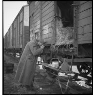 Un soldat mange debout près d'un wagon.