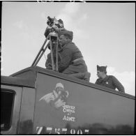 Un opérateur de prise de vue du SCA et son aide sont photographiés sur le toit du camion SCA immatriculé Z757207 en contre-plongée lors d'un tournage au fort du Télegraphe, sous le col du Galibier.