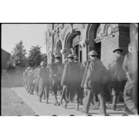 Des prisonniers alliés passent devant la gare du Cambrésis à Cambrai.