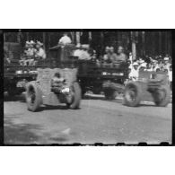 Passage de pièces d'artillerie tractées par des camions de transport lors du défilé du 14 juillet 1946 à Saigon.