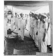 Dans le port de Saigon, lors d'une visite aux avisos "Le Chevreuil" et "La Gazelle" et à la frégate                  "Le Tonkinois", l'amiral Thierry d'Argenlieu passe en revue les troupes embarquées sur l'un des bâtiments. [description provisoire]