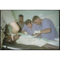 Intervention et opération chirurgicale sur un patient blessé à la main dans un dispensaire à Karama par les membres de l'antenne chirurgicale parachutiste (ACP).