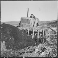 Chantiers de la Défense et Restauration des sols (DRS). Un engin Caterpillar ramène de la terre.