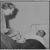 Alger. Arbre de Noël à l'hôpital Maillot. Remise de cadeaux à un grand blessé par madame de Menditte.