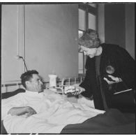 Alger. Arbre de Noël à l'hôpital Maillot. Madame Ailleret remet un cadeau à un grand blessé.