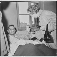 Alger. Arbre de Noël à l'hôpital Maillot. Remise de cadeaux à un grand blessé par madame de Menditte.