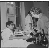 Alger. Arbre de Noël à l'hôpital Maillot. Madame de Menditte remet un cadeau à un grand blessé.