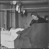 Alger. Arbre de Noël à l'hôpital Maillot. Remise de cadeaux à un grand blessé par madame  Ailleret.
