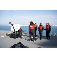 Des techniciens audiovisuels installent une antenne satellite sur le pont d'envol du porte-hélicoptèress amphibie (PHA) Tonnerre à Sète.
