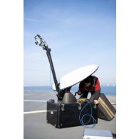 Un technicien audiovisuel installe une antenne satellite sur le pont d'envol du porte-hélicoptèress amphibie (PHA) Tonnerre à Sète.