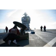 Des techniciens audiovisuels installent une antenne satellite sur le pont d'envol du porte-hélicoptèress amphibie (PHA) Tonnerre à Sète.