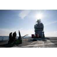 Des techniciens audiovisuels installent une antenne satellite sur le pont d'envol du porte-hélicoptèress amphibie (PHA) Tonnerre à Sète.