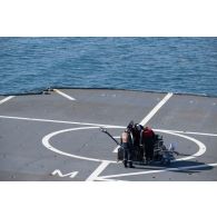 Des techniciens audiovisuels installent une antenne satellite sur le pont d'envol du porte-hélicoptèress amphibie (PHA) Tonnerre à Sète.