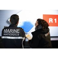 L'assistante de production Lola de l'ECPAD se coordonne avec un membre de l'équipage du porte-hélicoptèress amphibie (PHA) Tonnerre à Sète.