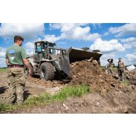 Des soldats britanniques des Royal Engineers creusent une tranchée au moyen d'un bulldozer light wheeled tractor (LWT) à Tapa, en Estonie.