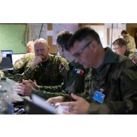 Un pilote de l'escadron de chasse 2/5 Île-de-France collabore avec son homologue de l'aviation royale du Canada au poste de commandement de l'exercice Orion 4 à Mailly-le-camp.