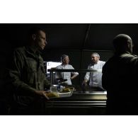 Des cuisiniers du groupement de soutien de base de Défense (GSBdD) d'Angoulême servent le repas des troupes à l'ordinaire du camp de Vouziers.