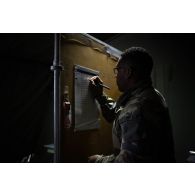 Un soldat note des informations sur un panneau sur le camp de Vouziers.