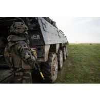 Un soldat du 16e bataillon de chasseurs (BCh) progresse à couvert d'un véhicule blindé de combat d'infanterie (VBCI) à Mourmelon.