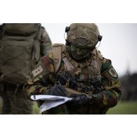 Un chef de section belge des chasseurs ardennais se repère au moyen d'une carte à Suippes.