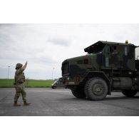Un soldat américain guide la circulation d'un porte-chars Oshkosh M1070A0 HET à Suippes.