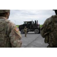 Un soldat américain guide la circulation d'un porte-chars Oshkosh M1070A0 HET à Suippes.