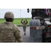 Un soldat américain guide la circulation d'un porte-chars Oshkosh M1070A0 HET à Suippes.