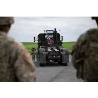 Un soldat américain guide la circulation d'un porte-chars Oshkosh M1070A0 HET à Suippes.