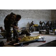 Un auxillaire sanitaire du Service de santé des armées (SSA) soigne un soldat simulant une blessure au Rôle 1 de Saint-Germainmont.