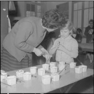 Le club du jeudi en Algérie. Une monitrice et une enfant avec des gobelets de peintures.
