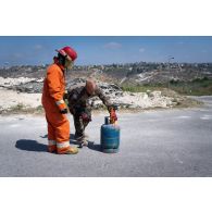 L'adjudant-chef Cédric de la brigade de sapeurs-pompiers de Paris (BSPP) démontre la fermeture d'une bouteille de gaz enflammée à un pompier malaisien à Marakah, au Sud-Liban.