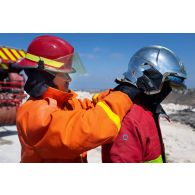 Un pompier malaisien aide son camarade à revêtir une tenue de feu de la brigade de sapeurs-pompiers de Paris (BSPP) pour un exercice à Marakah, au Sud-Liban.