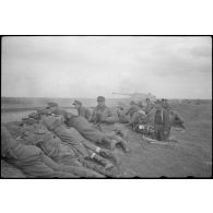 Un Nashorn du schwere Panzer Abteilung 519 tire, protégés par un talus des fantassins et des Panzergrenadier observent l'horizon aux jumelles.