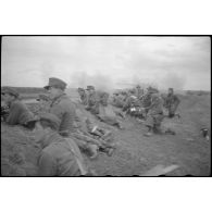 Un Nashorn du schwere Panzer Abteilung 519 tire, protégés par un talus des fantassins et des Panzergrenadier observent l'horizon aux jumelles.