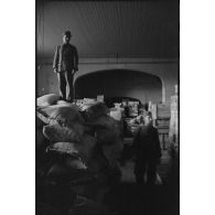 Au sein d'un magasin d'approvisionnement, des soldats entassent des sacs de farine.