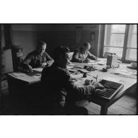 A l'intérieur de bureaux, des militaires et des civils s'occupent de la comptabilité du magasin d'approvisionnement.