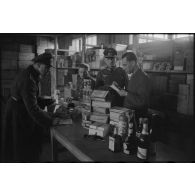Un officier récupère sa commande, les vivres sont rassemblés sur une table et contrôlées par le personnel du magasin.