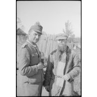 Un sous-officier de la Panzer Propagandakompanie 697 en compagnie d'un homme âgé.