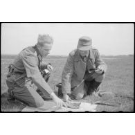 Un lieutenant-colonel (Oberstleutnant) et un capitaine se concentre devant une carte, un téléphone de campagne est à proximité.