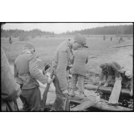 Alors que villageois requis réparent un pont de bois, des fantassins allemands le traversent.