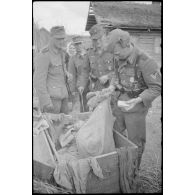 Des fantassins allemands fouillent les effets personnels de villageois.