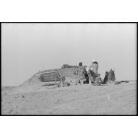 En raison des combats qui se déroulent à proximité, une femme et des enfants se tiennent à proximité d'un abri creusé dans le sol.
