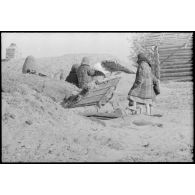 En raison des combats qui se déroulent à proximité, une femme et des enfants se tiennent à proximité d'un abri creusé dans le sol.