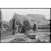 En raison des combats qui se déroulent à proximité, une femme et des enfants se tiennent à proximité d'un abri creusé dans le sol.
