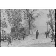 Dans la rue d'un village désert, des fantassins sont à la recherche de mines.